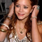 Woman wearing multiple gold bracelets, a beaded necklace, and a large turquoise ring.