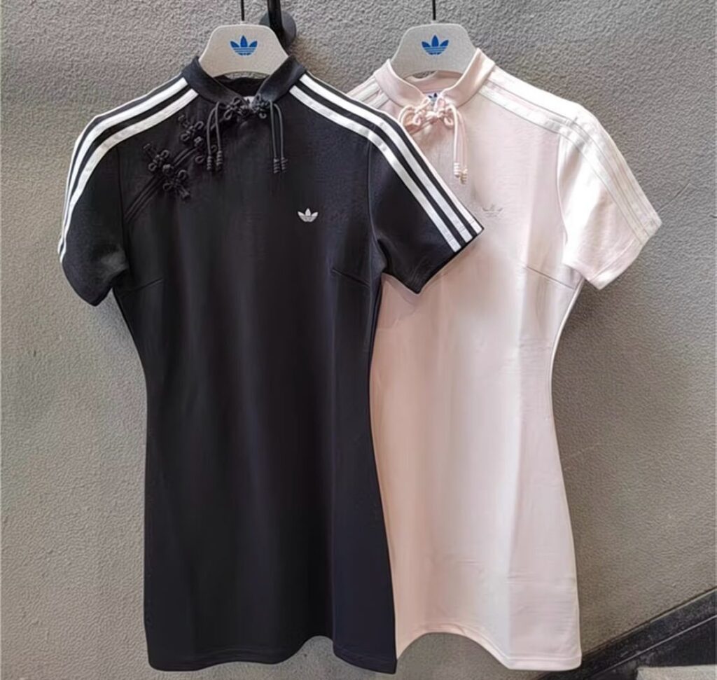 Black and pink adidas dresses with mandarin collars and shoulder stripes on hangers