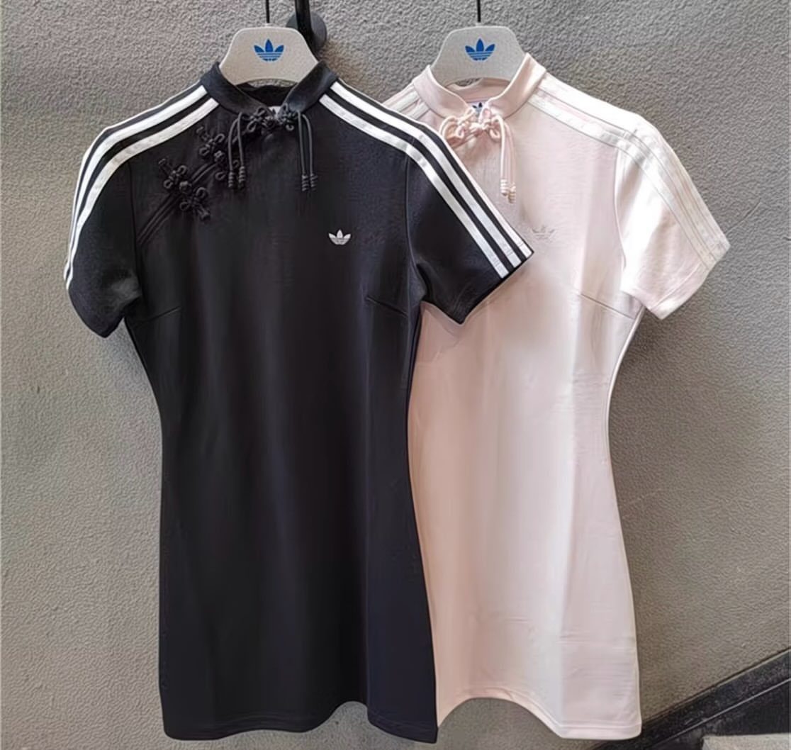 Black and pink adidas dresses with mandarin collars and shoulder stripes on hangers