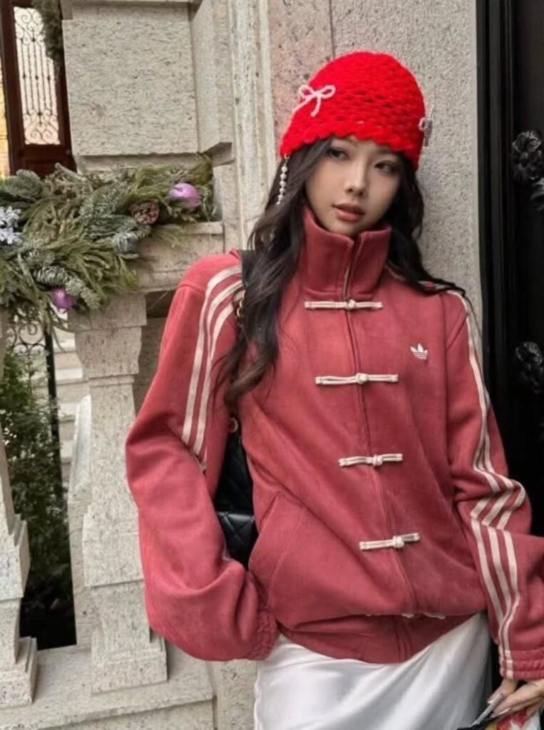 Woman wearing a red Adidas jacket with Chinese frog buttons and a red beanie.