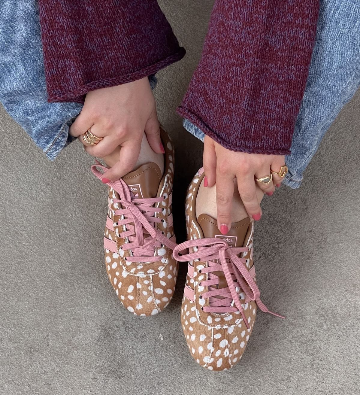 Animal print sneakers with pink laces worn with blue jeans and maroon sweater.