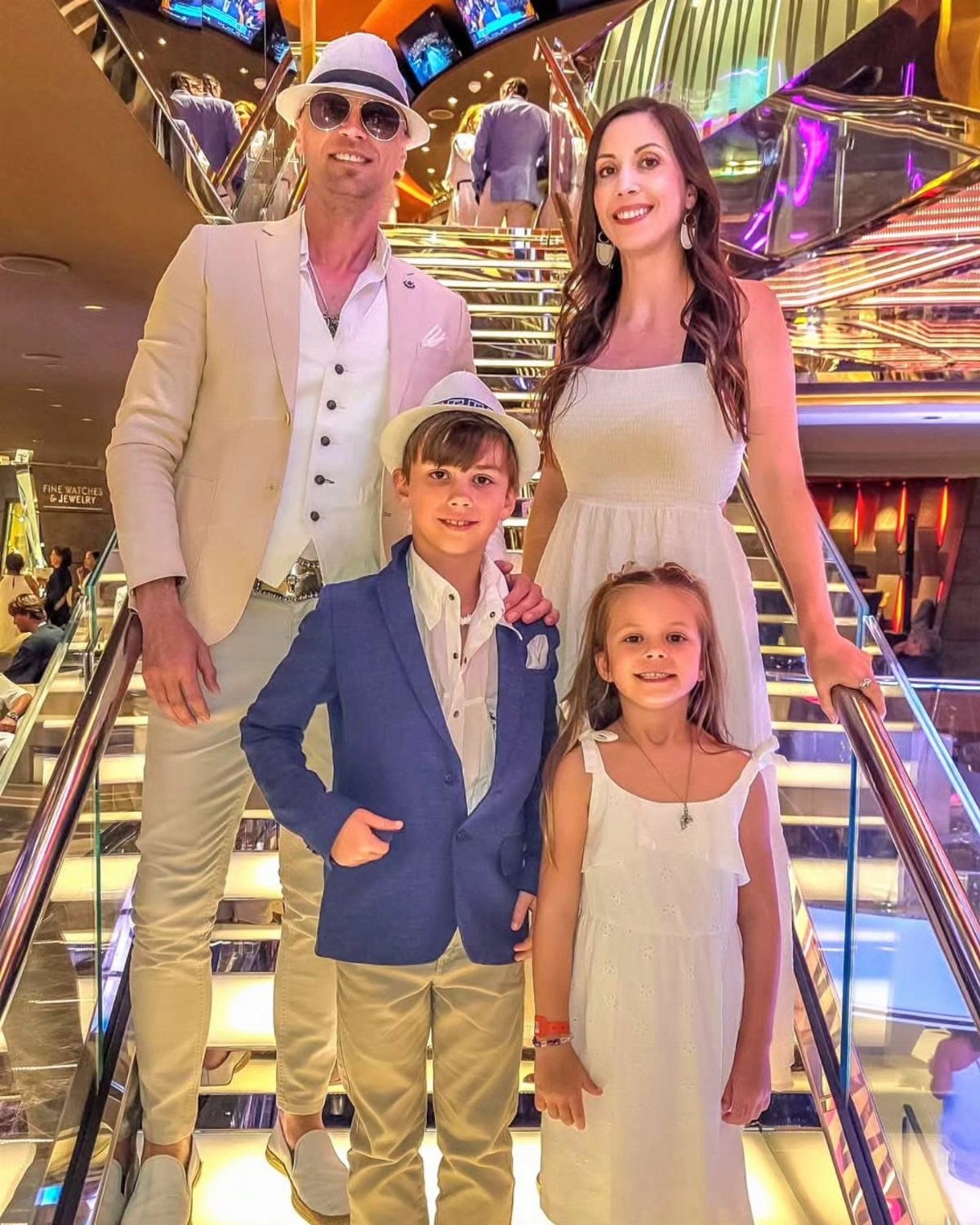 Family posing on cruise ship stairs with woman and girl in white dresses
