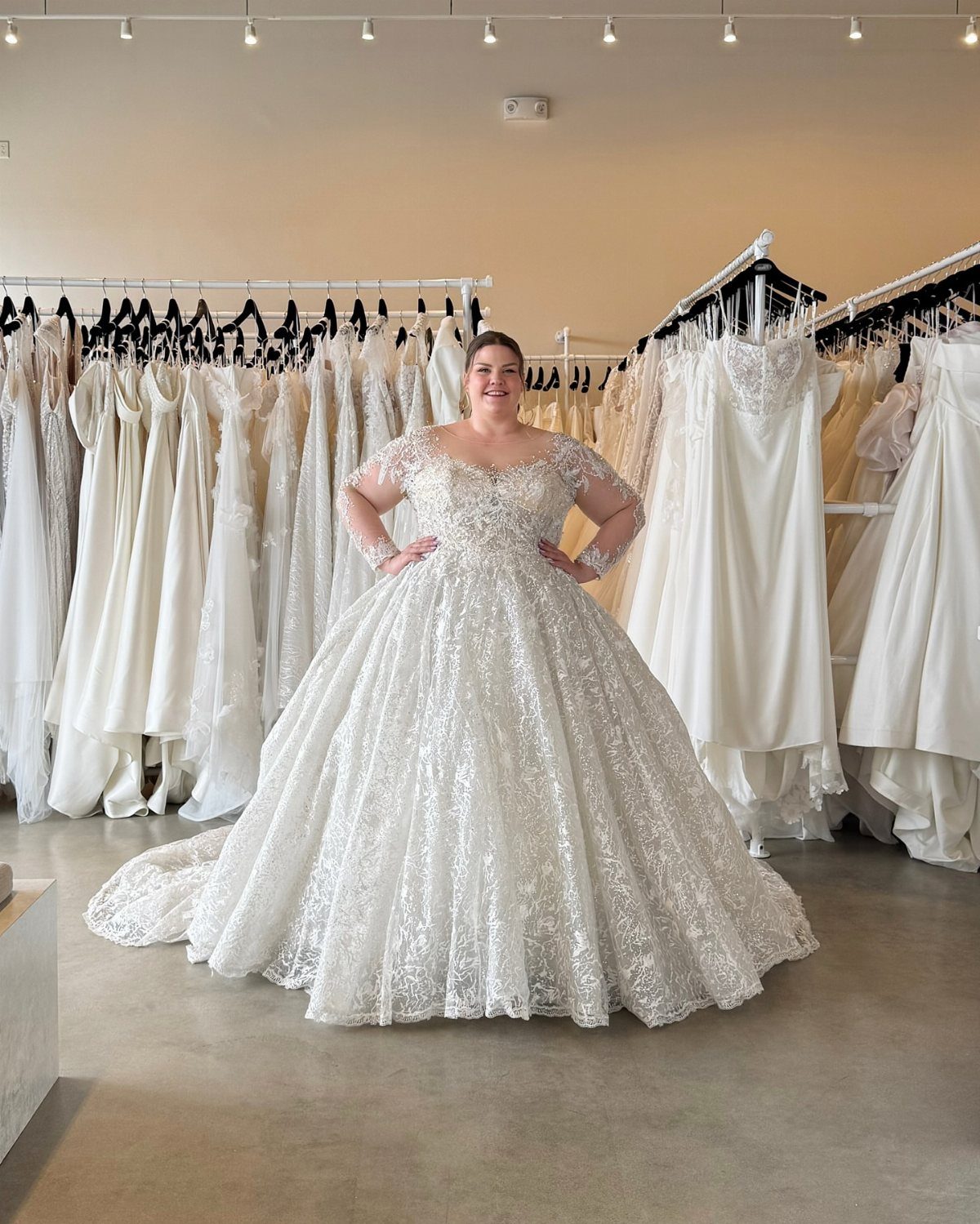 Woman wearing a voluminous white sparkling ballgown wedding dress in a bridal shop