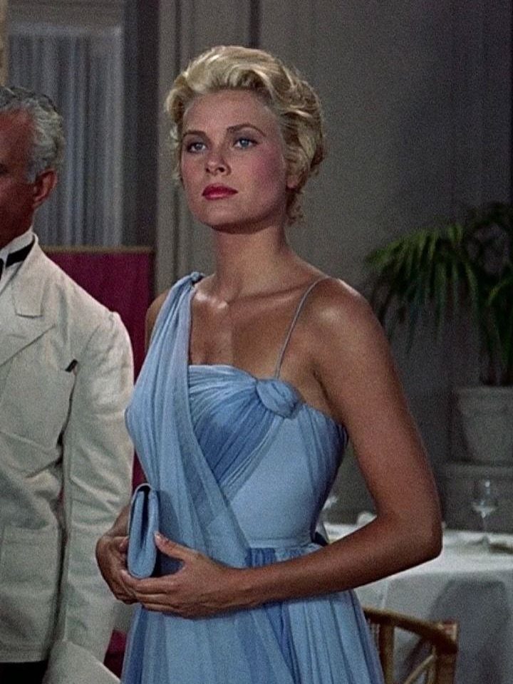 Woman in a light blue one-shoulder pleated gown and matching clutch.