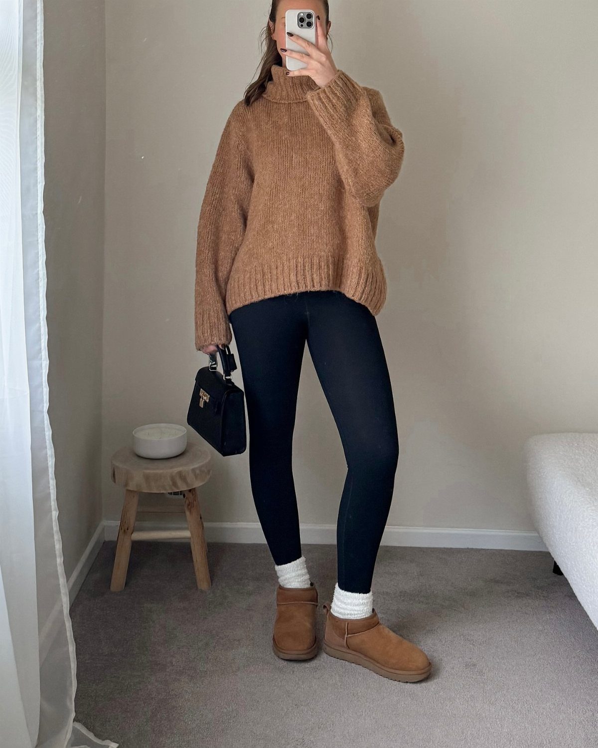 Person wearing a tan sweater, black leggings, and tan sheepskin boots in a room.