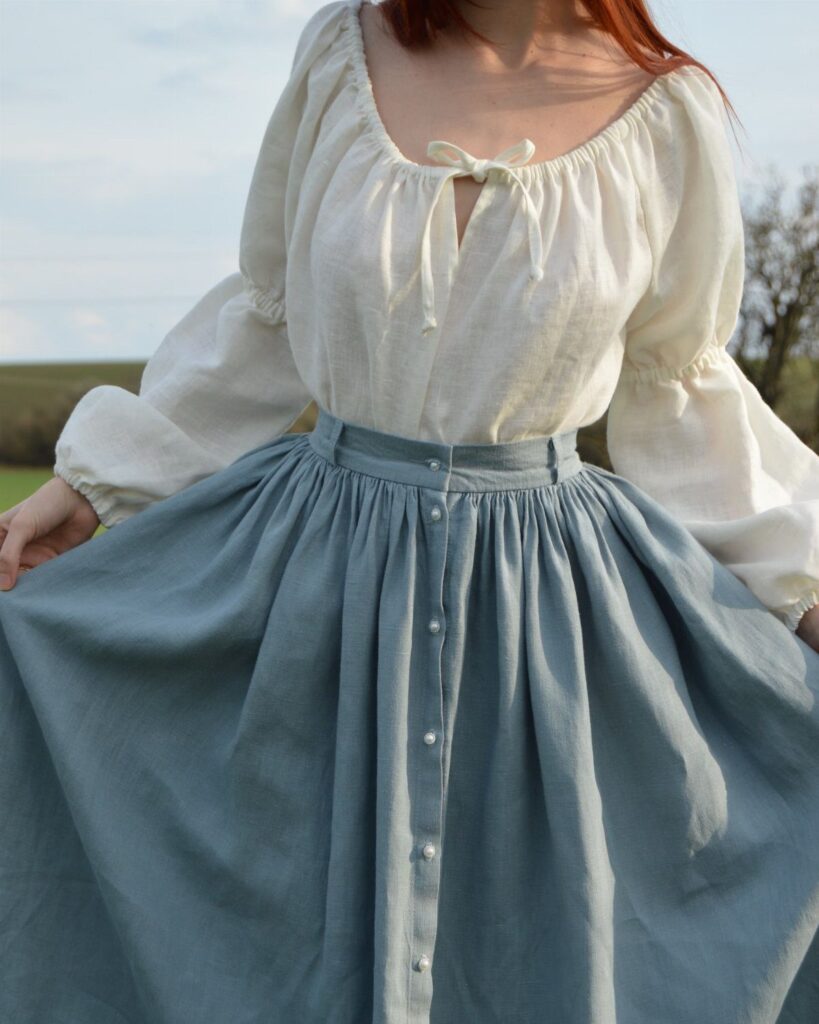 White linen blouse and blue button-down skirt worn by a person outdoors.