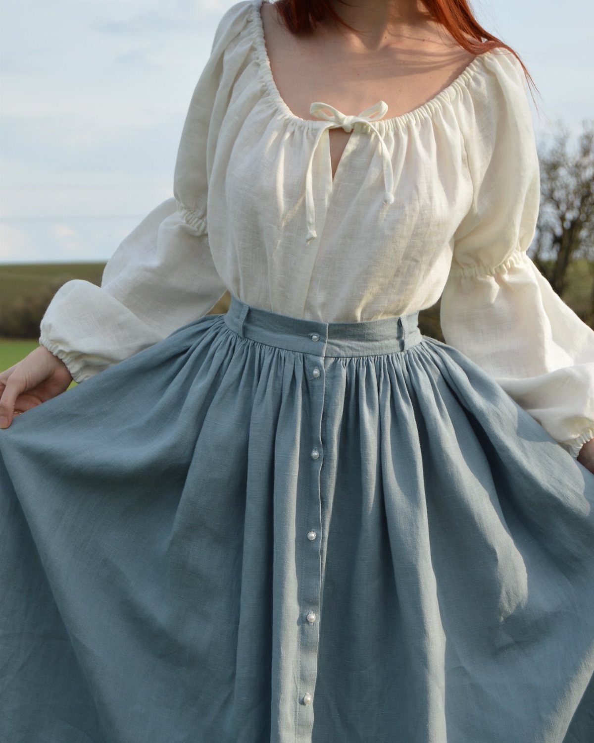White linen blouse and blue button-down skirt worn by a person outdoors.