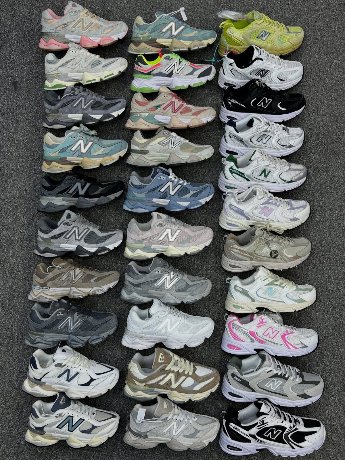 Various colored New Balance 9060 sneakers arranged in a grid on grey ground.