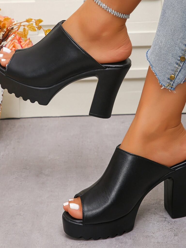 Black open-toe platform sandals with chunky block heels worn with blue denim jeans.