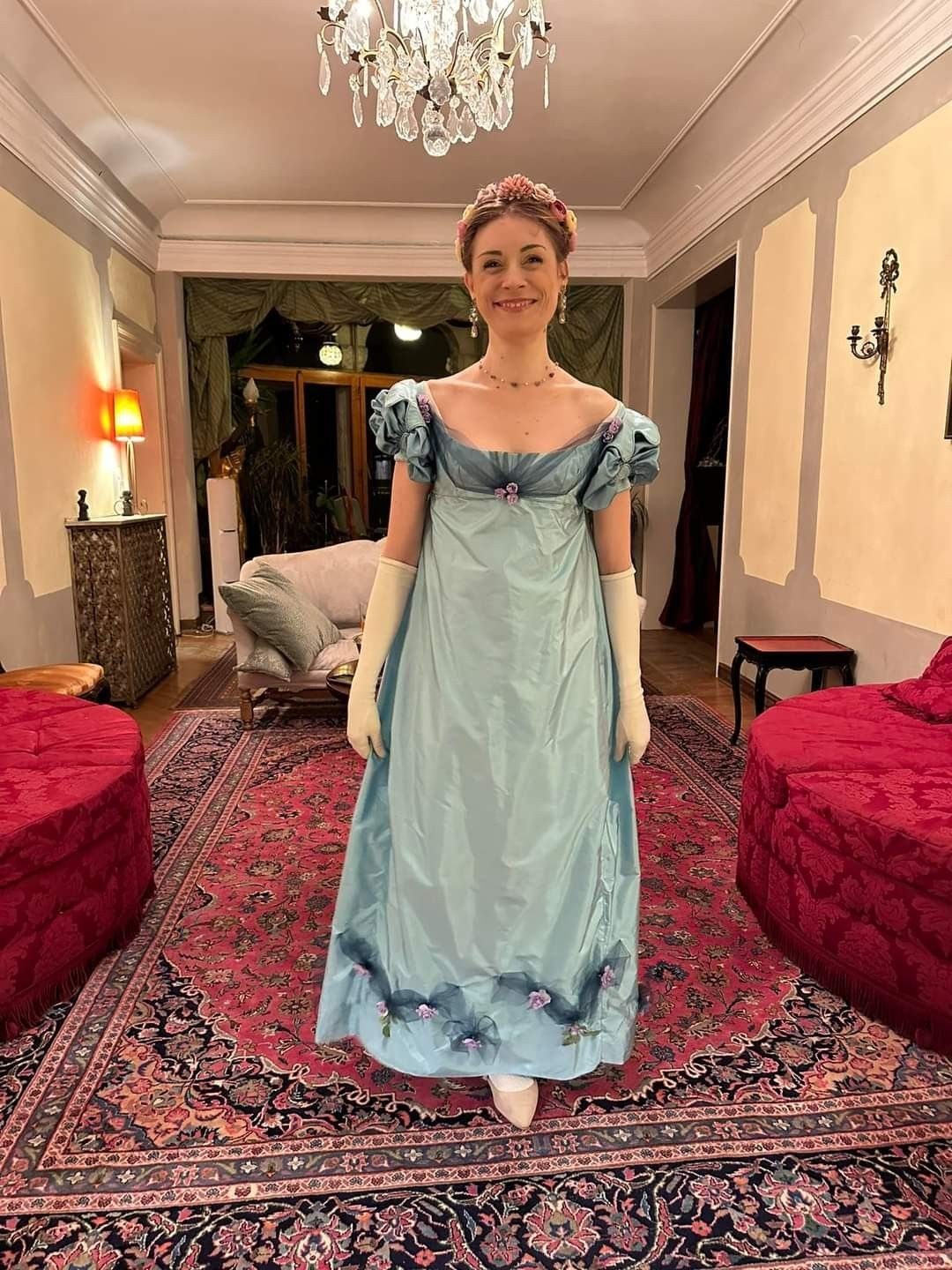 Woman in a light blue satin empire-waist gown with white opera gloves.
